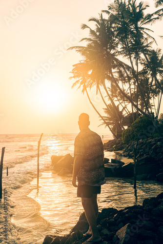 Male model  against the backdrop of palm trees and the setting sun  fashion photo  summer clothes.