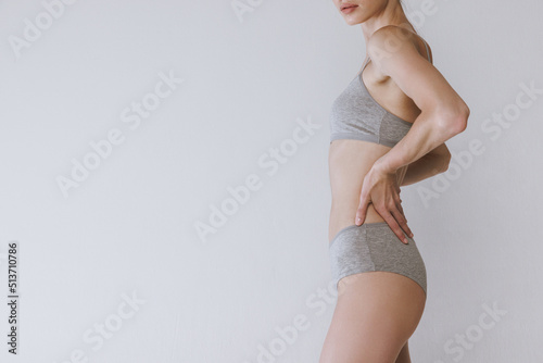 Fotografia Side view image of slender female body in underwear isolated over grey studio background