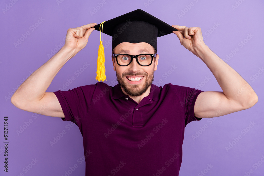 Photo of young cheerful man wear mortarboard degree graduate bachelor isolated over violet color background Photo of young cheerful man wear mortarboard degree graduate bachelor isolated over violet color background