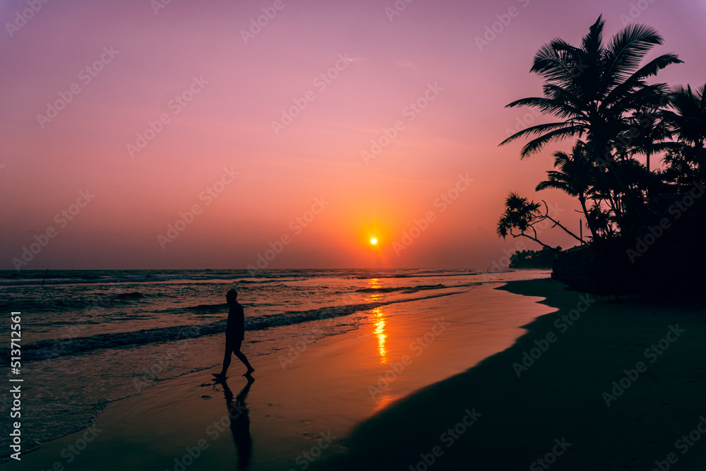 Male model walking on tropical beach at sunset, beautiful holiday landscape.