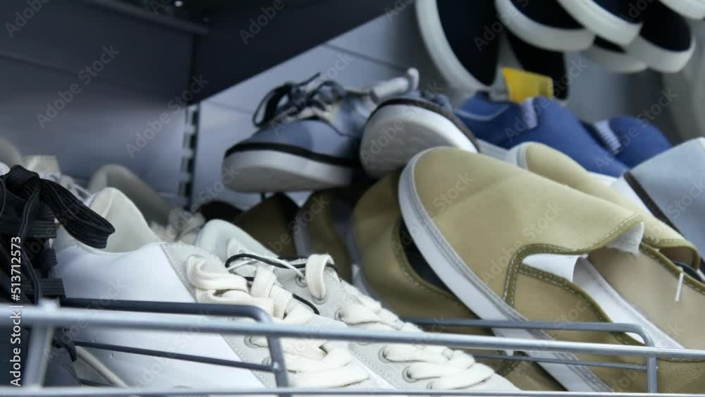 Close-up of white sneakers on the store shelf and a man takes them Close-up of white sneakers on the store shelf and a man takes them