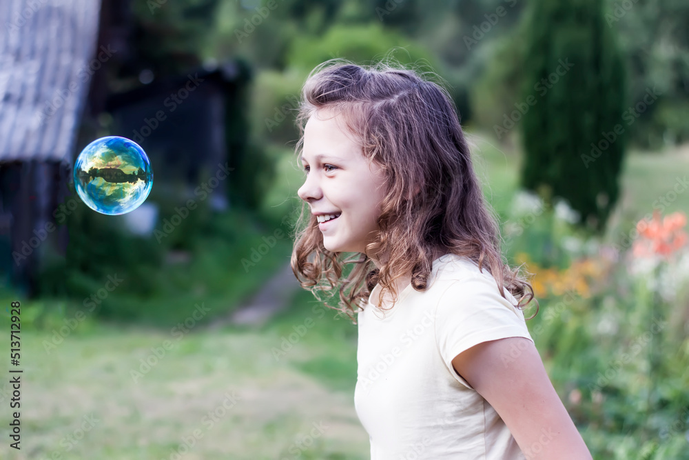 A school-age girl playing with soap bubbles outdoors. Positive emotions. A school-age girl playing with soap bubbles outdoors. Positive emotions.