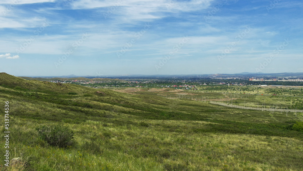 View of the city of Ust-Kamenogorsk (kazakhstan). Summer steppe. Green grass and blue sky. Hills. Cityscape View of the city of Ust-Kamenogorsk (kazakhstan). Summer steppe. Green grass and blue sky. Hills. Cityscape