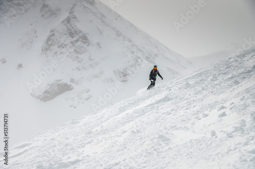 Young sportswoman snowboarder ride on a snowy slope against the backdrop of mountains on a winter day at a ski resort