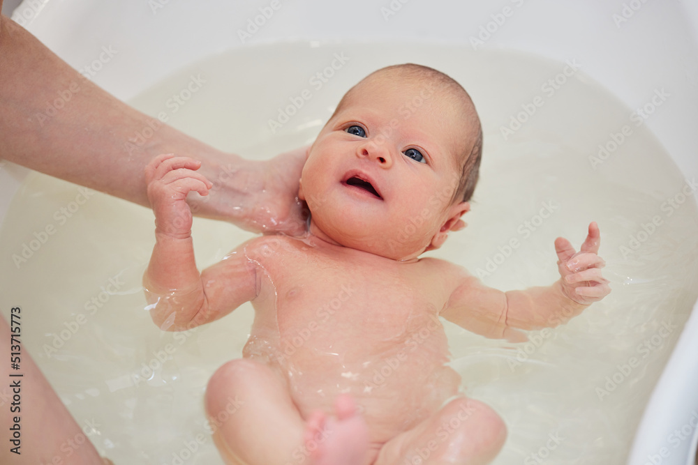 mother bathes her baby in a white small plastic tub mother bathes her baby in a white small plastic tub