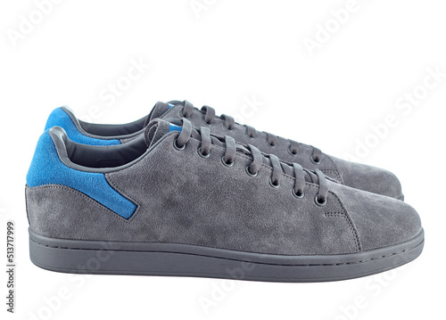 Beautiful pair of fashionable modern sneakers made of gray suede with inserts of bright blue suede in the back, lace-up, isolated on a white background. Side view.