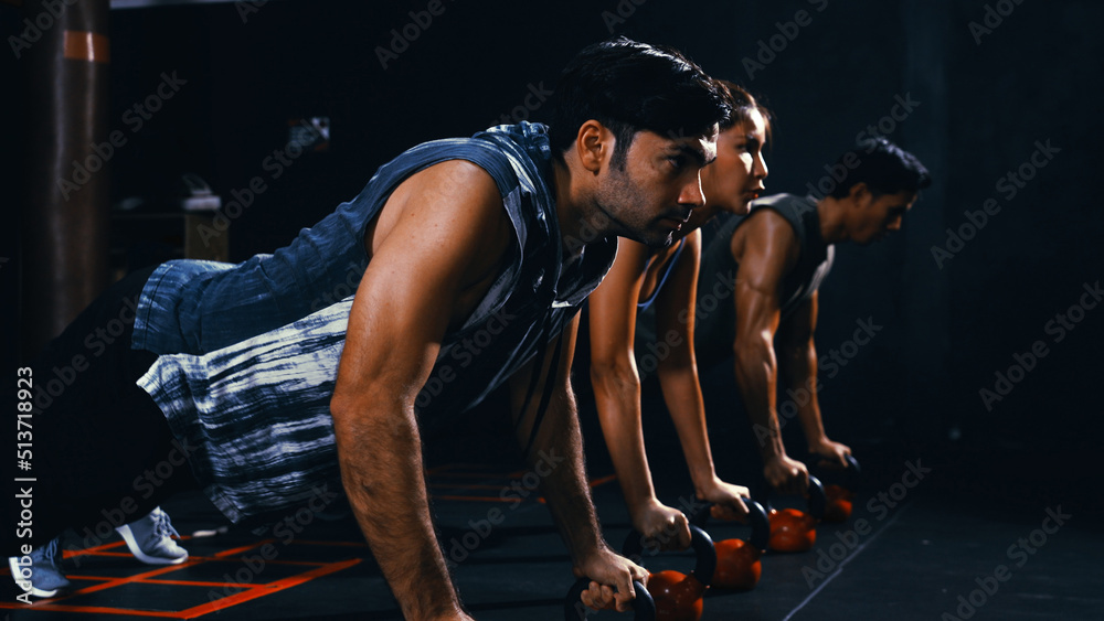 Sporty group of people doing push-ups on weights workout exercise in ...