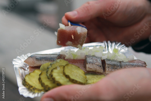 Photography Hand takes a piece of herring with a toothpick
