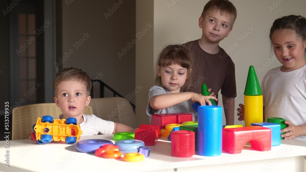 Fototapeta premium kindergarten. a group of children play toys cubes and cars indoor on the table in kindergarten. kid dream creative happy family preschool education concept. nursery baby toddler home