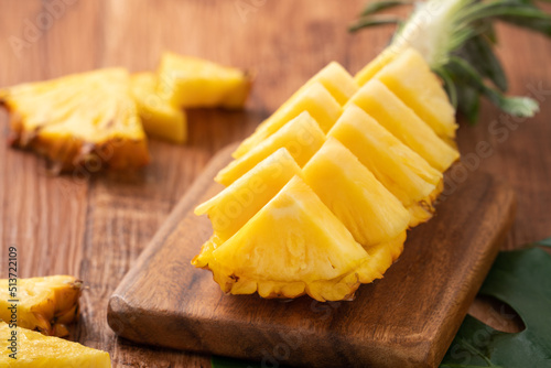 Fresh cut pineapple on a tray over dark wooden table background.