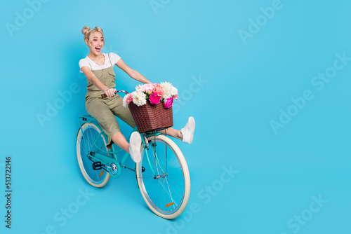 Full size photo of impressed blond lady ride bicyle wear t-shirt overall footwear isolated on blue background