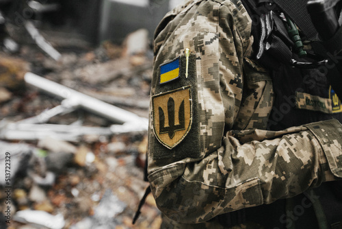 Ukrainian military woman with the Ukrainian flag in her hands on the background of an exploded house photo