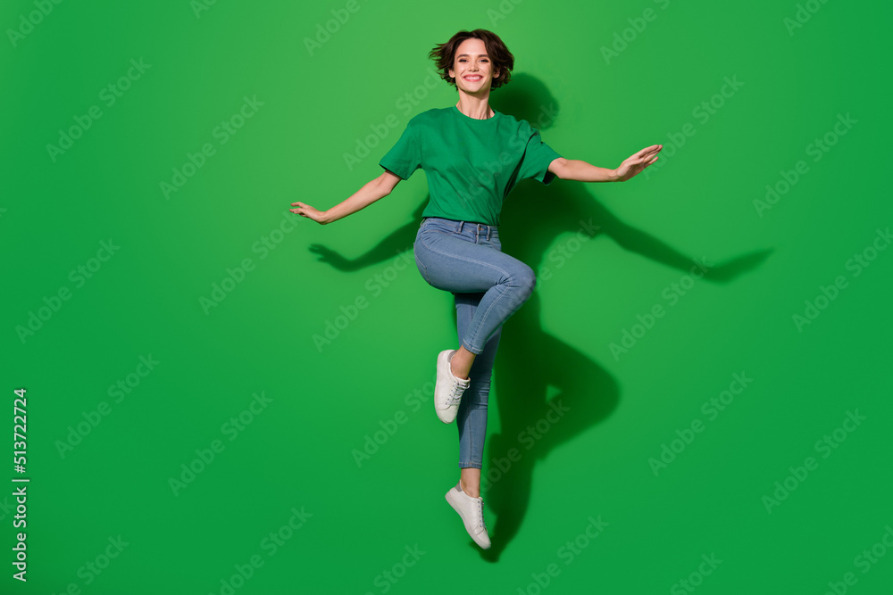 Full length photo of overjoyed glad person jumping have good mood isolated on green color background Full length photo of overjoyed glad person jumping have good mood isolated on green color background