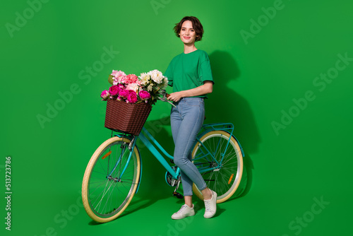 Full size photo of nice lovely girl standing near bike have good mood isolated on green color background