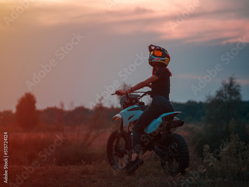 A young slender woman in a helmet on a cross - country motorcycle or pit bike . Moto woman