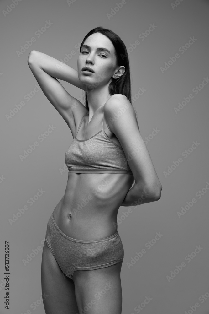 Naklejka premium Portrait of beautiful young woman with perfect slim body posing in underwear. Black and white photography