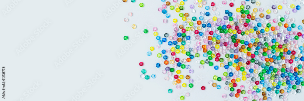 Banner with colorful beads scattered on a blue background. Equipment for handmade accessories.
