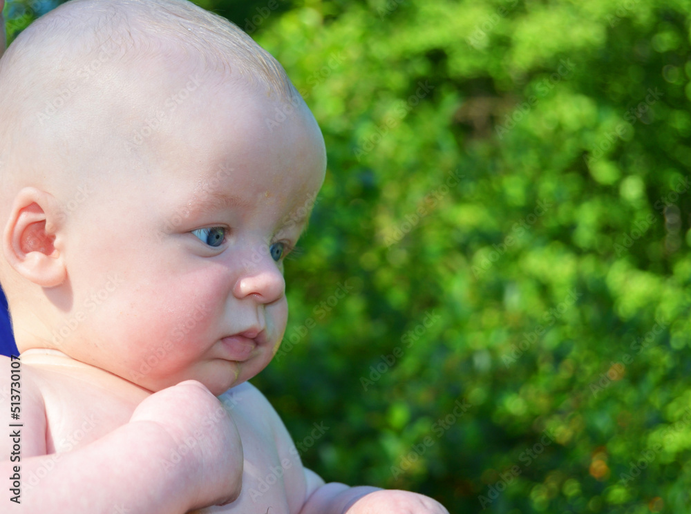 Cute baby looks with surprise in the summer in the park