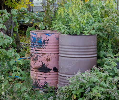 Rain water flows from a drainpipe to the metal barrel in garden in summer close up