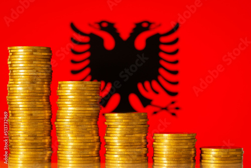 Stacks of coins forming negative graph against flag of Albania. Concept of economic regression, crisis in country photo