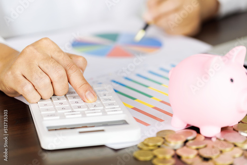 pig piggy bank on the table and woman calculating financial accounts for save money, saving money or savings concept.