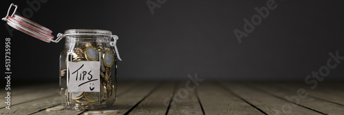Картината върху платно Glass tips jar full of coins on a wooden work top 3d render