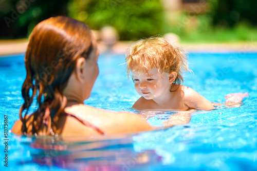 Summer outdoor fun in the pool in the villa. Happy child is having fun. Mom and daughter in the pool. A woman teaches a baby to float on the water and swim. Family happiness