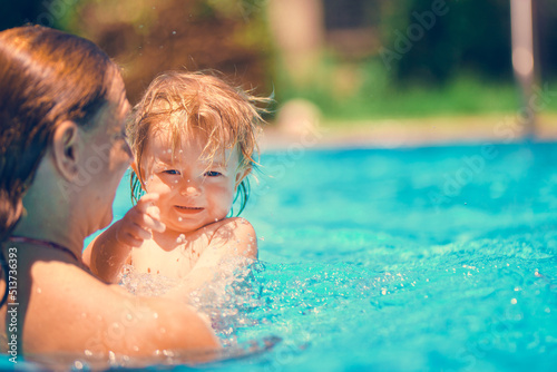 Family happiness. Happy child is having fun. Mom and daughter in the pool. Summer outdoor fun in the pool in the villa. A woman teaches a baby to float on the water and swim