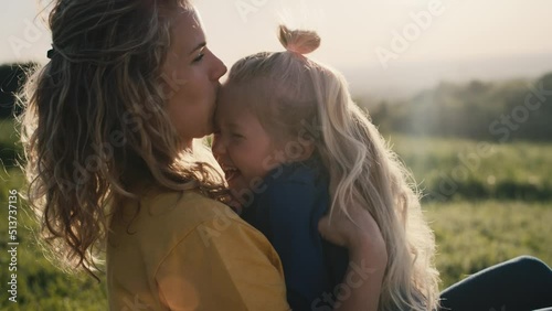 Mom with little daughter sitting on the meadow and bonding together. Shot with RED helium camera in 4K.   