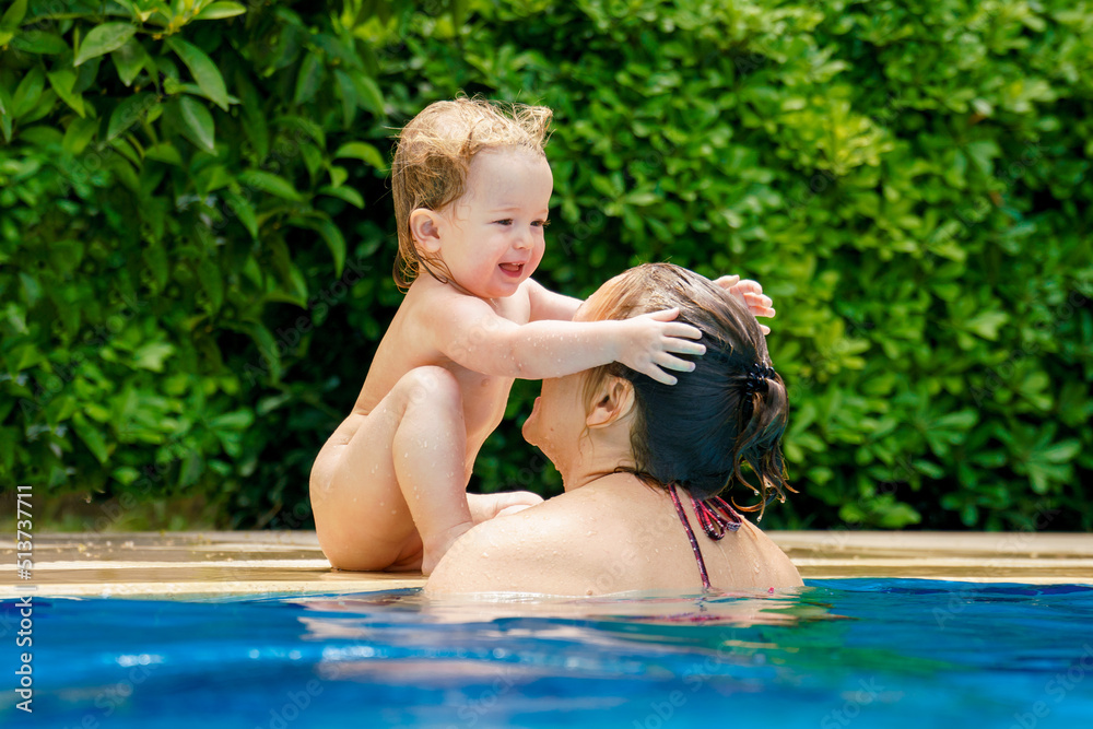 Happy child is having fun. Mom and daughter in the pool. Summer outdoor fun in the pool in the villa. Family happiness. A woman teaches a baby to float on the water and swim