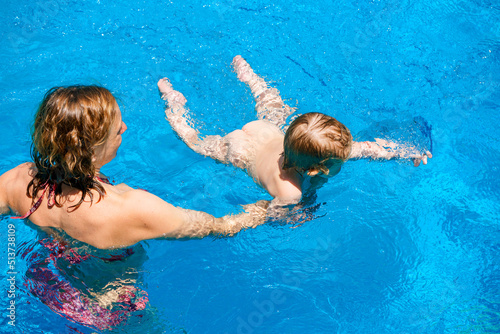 Happy child is having fun. Family happiness. Mom and daughter in the pool. A woman teaches a baby to float on the water and swim. Summer outdoor fun in the pool in the villa