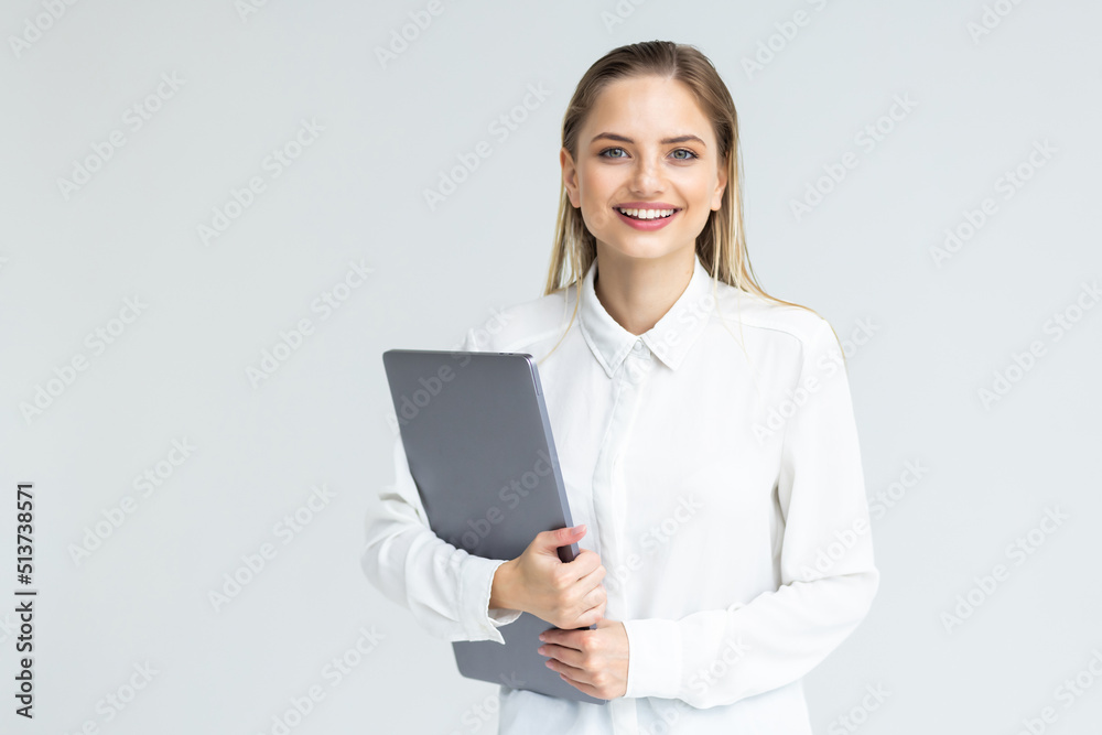 Portrait of a smiling businesswoman carrying laptop while standing isolated over white background Portrait of a smiling businesswoman carrying laptop while standing isolated over white background