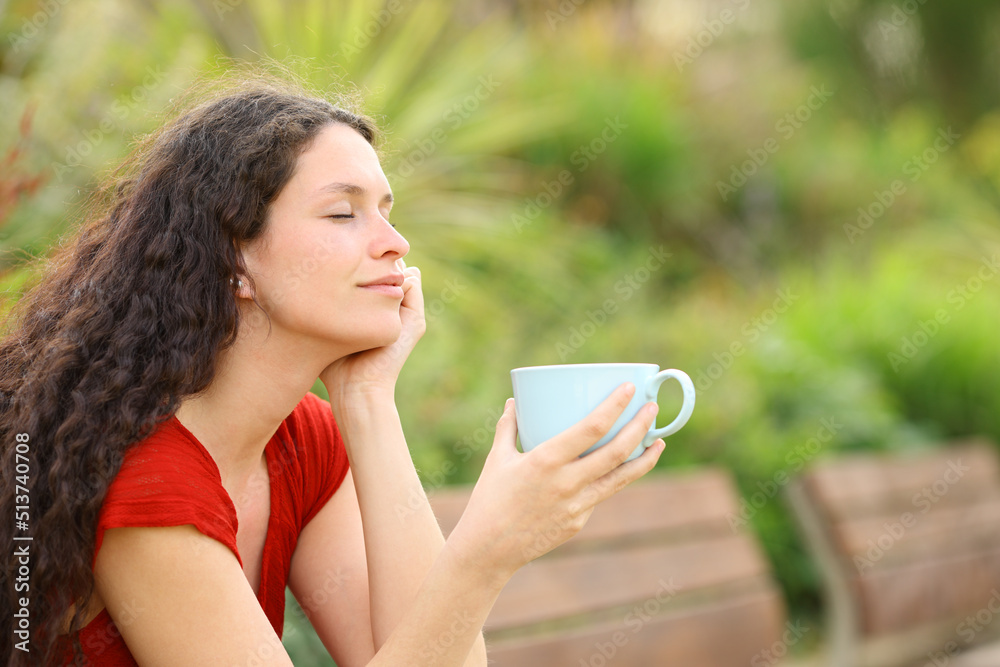 Relaxed woman in a park holding coffee mug Relaxed woman in a park holding coffee mug