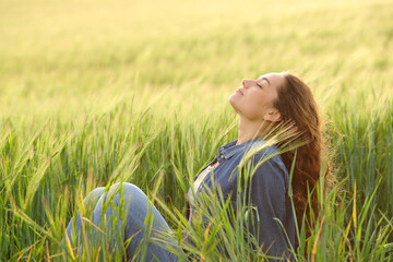Woman sitting in a wheat field breathing fresh air