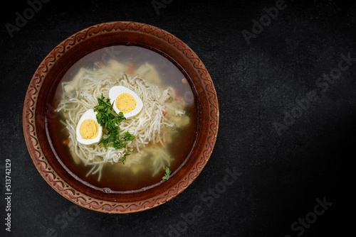 Chicken broth, with noodles, herbs and egg, studio light