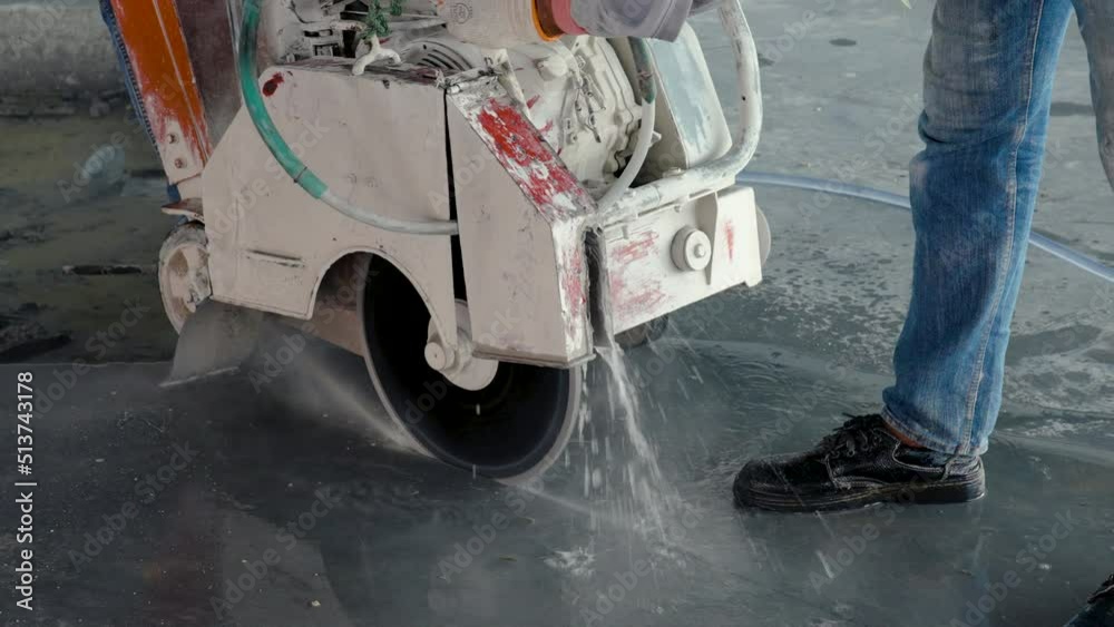 4K, Close Up machine is being operated cut the concrete. The small-blade Warsaw cutter is slitting the floor under the control of an Asian engineer. use water to prevent dust on the construction site 4K, Close Up machine is being operated cut the concrete. The small-blade Warsaw cutter is slitting the floor under the control of an Asian engineer. use water to prevent dust on the construction site