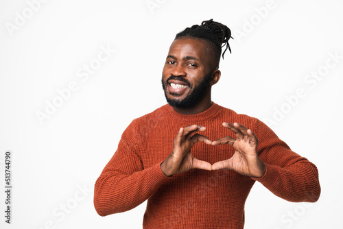 Happy african-american young man with dreadlocks in red sweater showing heart-shape gesture for love passion care isolated in white background