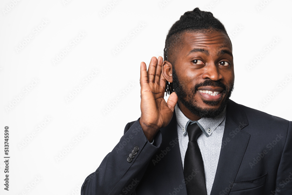 Cheerful african-american young businessman freelancer ceo boss leader bank manager in formal suit listening overhearing gossips rumors isolated in white background. Secret concept Cheerful african-american young businessman freelancer ceo boss leader bank manager in formal suit listening overhearing gossips rumors isolated in white background. Secret concept
