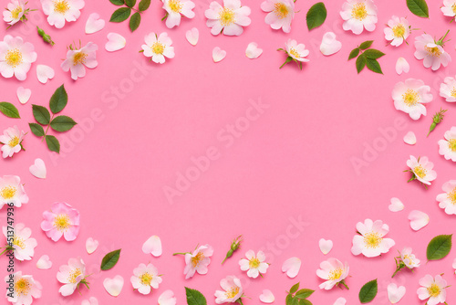 Rose flowers frame border, leaves buds and heart shaped petals on pink background top view flat lay