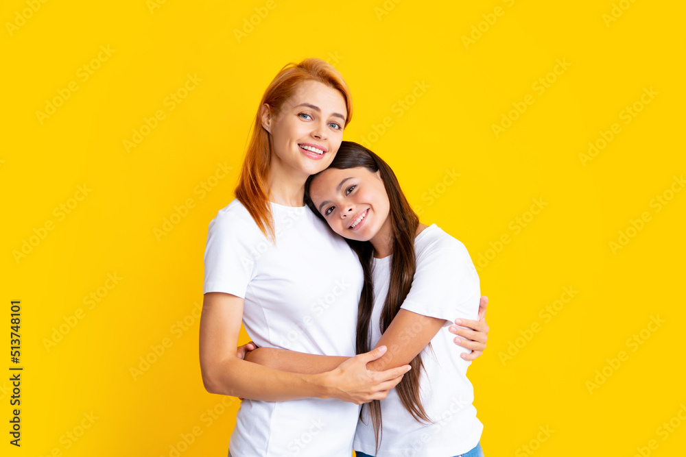 Beautiful mother and daughter smiling happy hugging over isolated yellow background. Beautiful mother and daughter smiling happy hugging over isolated yellow background.