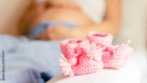 Pregnancy baby shoes. Happy pregnant woman holding pink baby shoes. Small child shoe. Concept of pregnancy, maternity, expectation for baby birth.