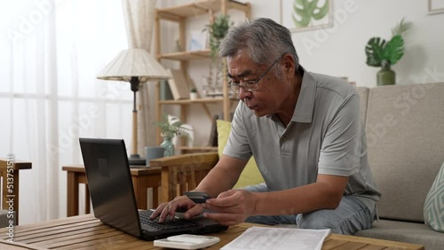old asian man using laptop and credit card payment shopping online with customer network connection. Older people with technology. senior male using debit card paying internet bargain sale