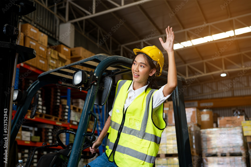 Asian women staff worker in uniform and yellow helmet in warehouse, smiling and waving somebody greetings. Asian women staff worker in uniform and yellow helmet in warehouse, smiling and waving somebody greetings.