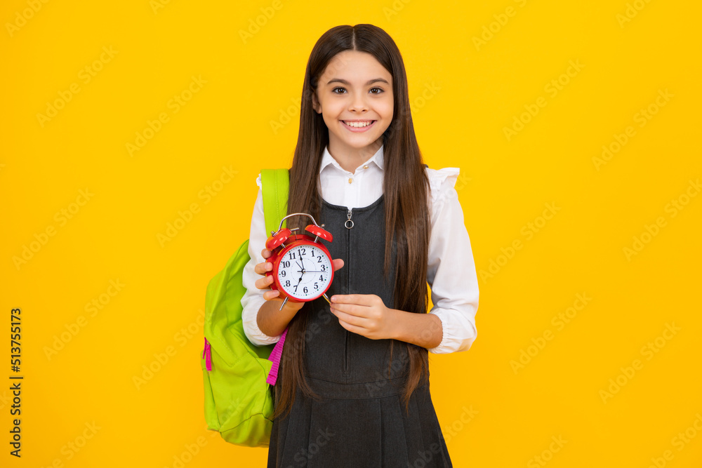 Happy girl face, positive and smiling school girl isolated on yellow. Back to school. Schoolchild, teenage student girl with clock alarm, time to study. Happy girl face, positive and smiling school girl isolated on yellow. Back to school. Schoolchild, teenage student girl with clock alarm, time to study.