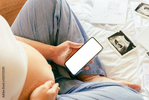 Pregnancy smartphone mockup. Pregnant woman holding smartphone. Mobile pregnancy online maternity application mock up. Concept of pregnancy, maternity, expectation for baby birth. © Maksym