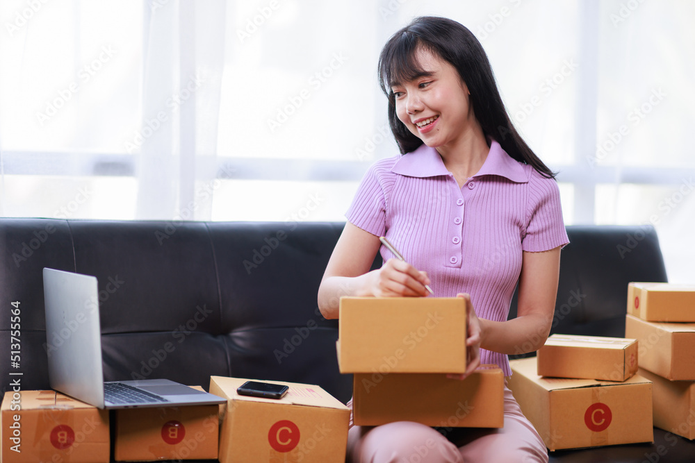 Startup SME small business entrepreneur of freelance using a laptop with box, Asian business woman on sofa check online orders to prepare to pack the boxes sell to customers sme business ideas online. Startup SME small business entrepreneur of freelance using a laptop with box, Asian business woman on sofa check online orders to prepare to pack the boxes sell to customers sme business ideas online.