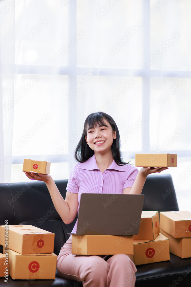 Startup SME small business entrepreneur of freelance using a laptop with box, Asian business woman on sofa check online orders to prepare to pack the boxes sell to customers sme business ideas online. Startup SME small business entrepreneur of freelance using a laptop with box, Asian business woman on sofa check online orders to prepare to pack the boxes sell to customers sme business ideas online.