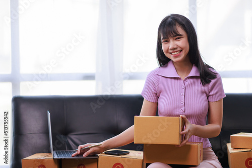 Startup SME small business entrepreneur of freelance using a laptop with box, Asian business woman on sofa check online orders to prepare to pack the boxes sell to customers sme business ideas online. © David