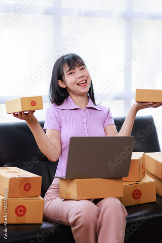 Startup SME small business entrepreneur of freelance using a laptop with box, Asian business woman on sofa check online orders to prepare to pack the boxes sell to customers sme business ideas online.