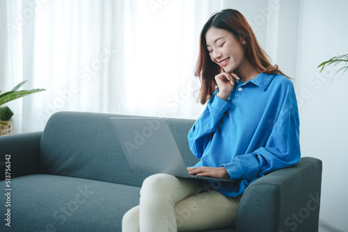 Free Download girl sitting on the sofa at home working on the computer. beautiful smile - GFXLoad
